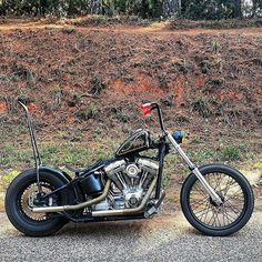 a black motorcycle parked on the side of a road next to some grass and bushes