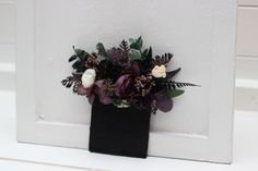 a black vase filled with flowers on top of a white countertop next to a door