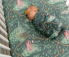 a baby sleeping in a crib next to a wall with castle designs on it