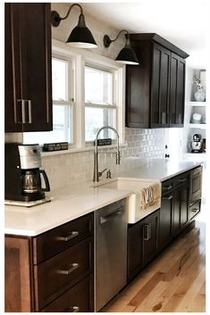 a kitchen with dark cabinets and white counter tops, along with stainless steel dishwasher