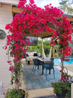 an outdoor dining area with pink flowers on the arbor