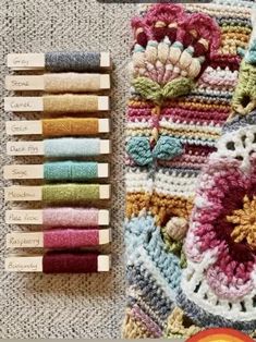 the crocheted blanket is next to several skeins of thread and markers