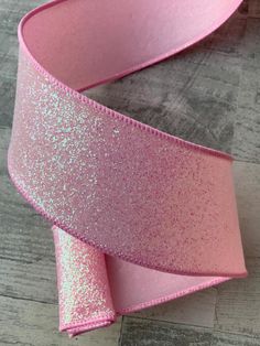 a pink glitter ribbon on a wooden surface