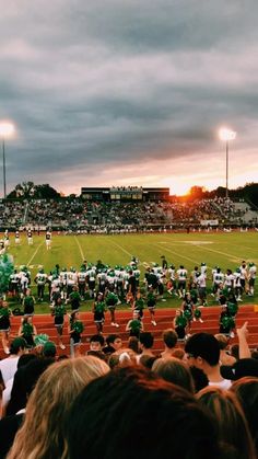 a football game is being played on a cloudy day with people watching from the bleachers