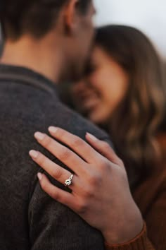 a man and woman embracing each other with their engagement ring