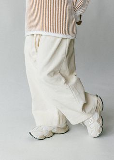 a person wearing white pants and a sweater