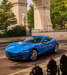 a blue sports car parked in front of an arch