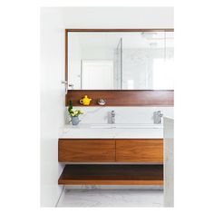 a bathroom with a sink, mirror and wooden cabinetry on the wall in front of it