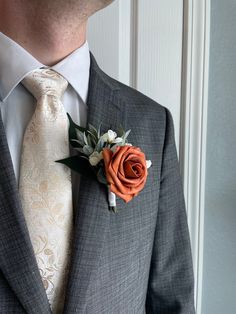 a man wearing a gray suit with an orange boutonniere on his lapel