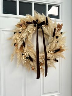 a white door with a brown ribbon hanging from it's side and a wreath on the front door