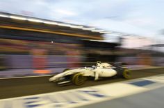 a blurry photo of a race car driving down the track in front of an audience