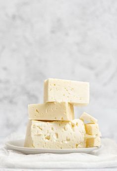 several pieces of tofu stacked on top of each other in a white plate with a marble background