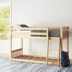 a wooden bunk bed sitting on top of a rug next to a bag and window