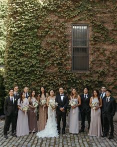 a group of people standing next to each other in front of a building with ivy growing on it