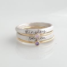 Cursive Name Stackable Birthstone Ring Set This set includes four rings! You will receive two name rings in fine silver (.999) engraved in our cursive font. These tarnish much slower than sterling silver since they have less copper. You will also receive two skinny cz birthstone rings in 14K yellow gold filled. These rings are handmade in our Indiana studio. Each engraved ring starts from a spool of wire. They are handcut, handformed and soldered in the first process of creating your ring. They Name Rings Personalized, Stackable Name Rings, Stackable Birthstone Rings, Birthstone Stacking Rings, Birthstone Rings, Name Ring, Cursive Font, Mother Rings, Basic Jewelry