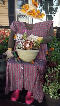 a scarecrow holding a bowl of flowers on the porch