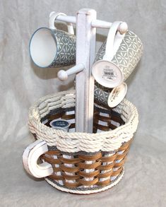 a basket with two mugs and some other items in it on a white background