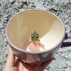 a person holding a cup with a small frog in it