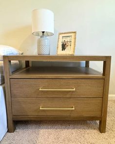 a night stand with two drawers and a lamp on the end table next to it