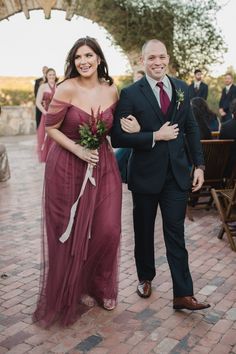 a man in a suit and tie standing next to a woman in a red dress