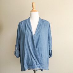 Boutique Wrap Front Blue Chambray Top By Hayden Los Angeles. Crossover Wrap Front With Tacking At Bust High Low Hemline Rolled Sleeves With Button Tab. Loose, Oversized Fit Cotton Gauze Chambray Light Denim Fabric And Buttons On Sleeve Tab New Boutique Item With Tags 100% Cotton Hand Wash Size Large Play It Cool In The Blue Chambray Wrap Top From Hayden. Trendy Washed Blue Blouse For Spring, Chic Cotton Light Indigo Top, Light Wash V-neck Top For Day Out, Light Indigo Tops For Spring Day Out, Chic Light Indigo Cotton Tops, Blue V-neck Denim Top For Summer, Light Blue Denim Tops For Work, Trendy Denim Blue V-neck Top, Chic Medium Wash Tops For Day Out