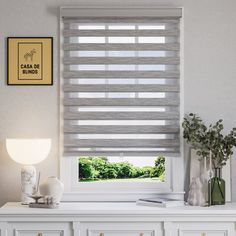 a white dresser with drawers and a window covered in blinds