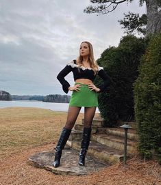 a woman standing on top of a rock next to a tree and grass covered field