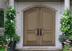 a large wooden door in front of some flowers