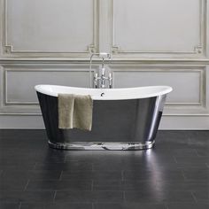 a black and white bath tub sitting on top of a tiled floor next to a wall