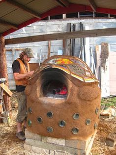 a man standing in front of an outdoor oven