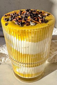 a yellow dessert sitting on top of a white table next to a glass container filled with nuts