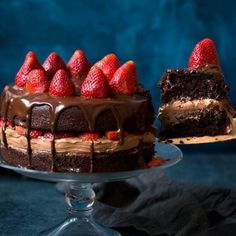 a cake with chocolate frosting and strawberries on top, next to a piece of cake