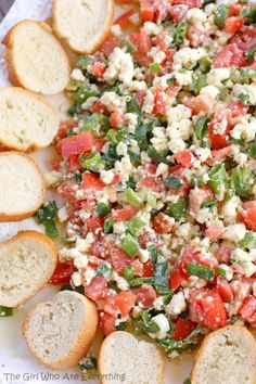 a plate full of bread and salad with tomatoes, green beans, and feta cheese