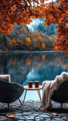 two chairs sitting next to each other near a lake