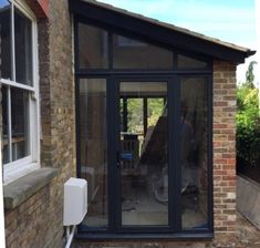 a brick building with an open glass door and side entrance to the back patio area