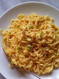 a white plate topped with pasta and parsley on top of a marble countertop