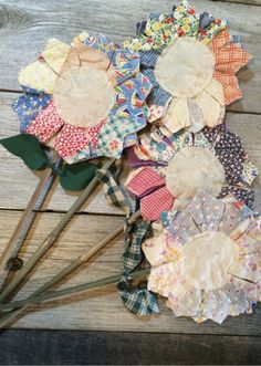 several pieces of fabric sitting on top of a wooden table next to flowers and scissors