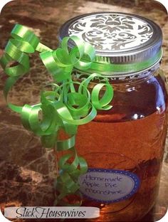 a jar filled with honey sitting on top of a counter next to a green ribbon