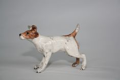 a white and brown dog figurine on a gray background