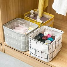 two storage bins on the floor next to each other with clothes and towels in them