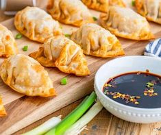 several dumplings on a cutting board with dipping sauce