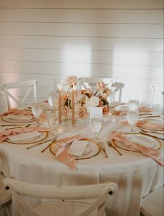 the table is set with white and gold plates, pink napkins, and flowers