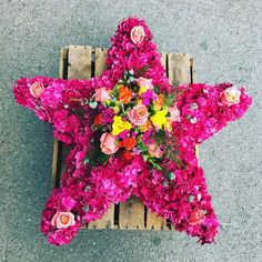 a star shaped arrangement of flowers on top of a wooden pallet in the street