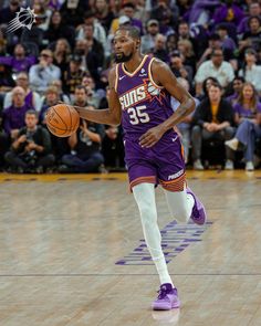 a basketball player dribbling the ball in front of an arena full of people