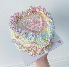 a hand holding a cake decorated with flowers and hearts that says happy mother's day