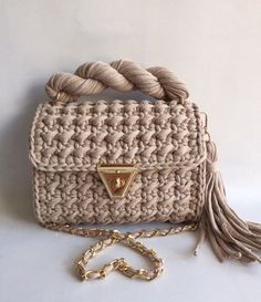 a crocheted purse with a tasseled handle and gold tone hardware, on a white background