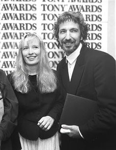 three people standing next to each other in front of a wall with awards on it