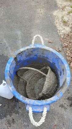 a bucket filled with sand sitting on top of a street next to a white container