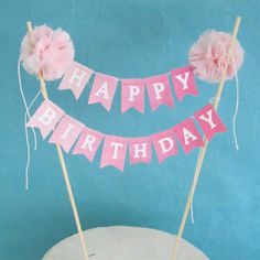 a birthday cake decorated with pink flowers and bunting banner that says happy birthday on it