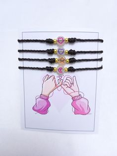 three bracelets with black cords and gold beads on top of a white card that says love